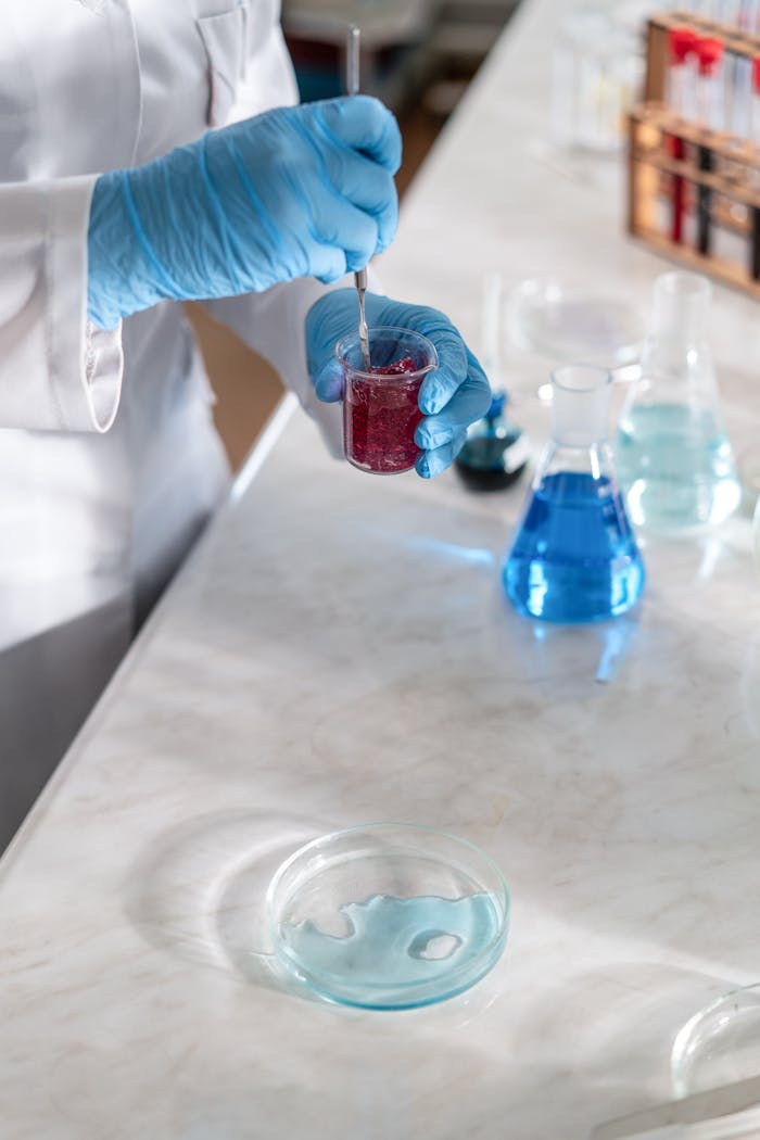 Scientist wearing gloves mixing chemicals in laboratory setting.