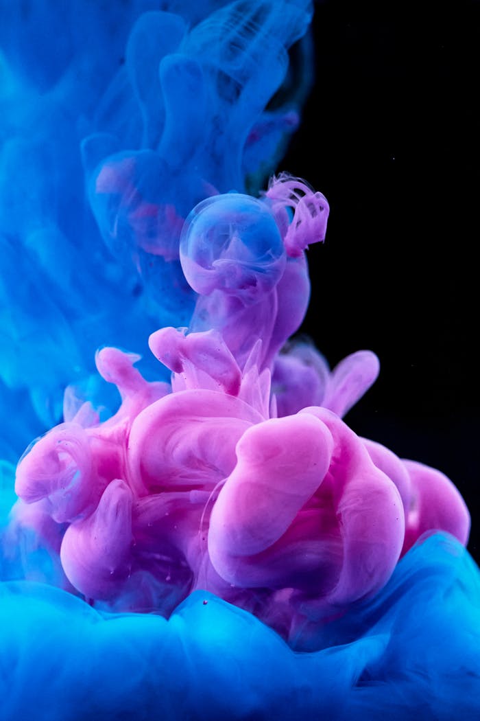 About Vibrant abstract photo of pink and blue ink mixing underwater.